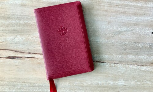 a red book with a tassel on top of a wooden table